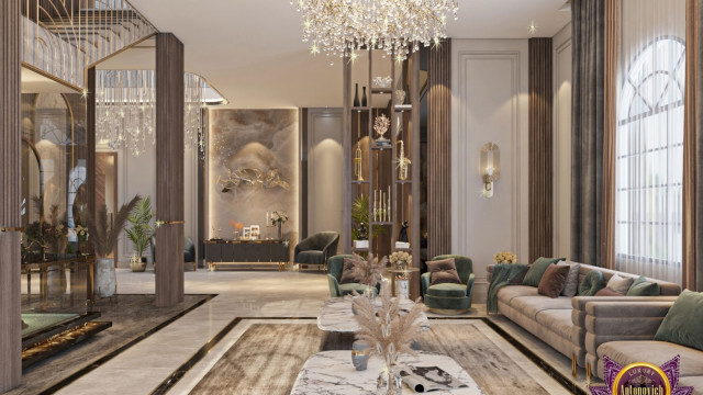 This picture shows an interior design of a modern luxury apartment. The room features several stylishly designed furniture pieces and fixtures, including a large blue velvet sofa, two armchairs, a glass coffee table, a circular rug, and several framed wall art pieces. Light colored hardwood flooring with light gray walls provides a neutral base for the bright pops of color in the furniture and rugs. The ceiling is finished in a deep, dark wood, providing a nice contrast to the lighter elements in the room.