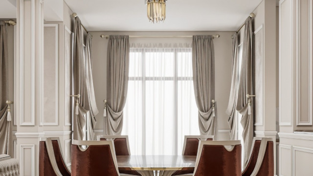 This picture shows a modern bedroom designed with luxury and elegance in mind. The walls are painted in a light grey color and feature several abstract art pieces, creating a cozy and inviting atmosphere. The bed is upholstered in a velvet material that features a deep jewel tone and stands out against the neutral tones of the walls. The nightstands match the bed and feature glass tops, while the chest of drawers includes a rich wood material. A unique yellow chandelier hangs from the ceiling, bringing a touch of glamour to the room.