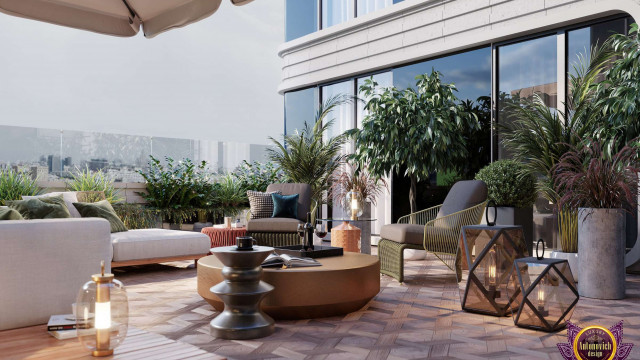 This picture is of a luxurious, modern living room. The color scheme consists of warm gray walls and white ceiling complemented by wood furniture and wood floors. The furniture includes two sectional sofas in a corner configuration, glass-topped coffee table, floor lamp, and two armchairs. The living room also features a stunning crystal chandelier, decorative mirrors, glass-enclosed shelving units, and a large area rug with an abstract pattern. There is a fireplace with a marble mantle and the windows are adorned with elegant drapes.