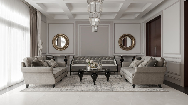 This picture shows a modern living room designed by Antonovich Design. The room features a white sofa with accent pillows, a glossy white coffee table, and two armchairs upholstered in a subtle gray pattern. The walls are painted a light gray color and the floor is covered in a gray and white geometric patterned rug. A unique, glass-encased chandelier hangs above the seating area, adding a touch of glamour to the room.