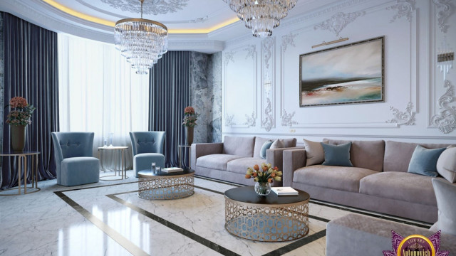 This image shows a contemporary living room with a modern and luxurious design. The room is outfitted with a white leather sofa and armchair, sitting on a beige area rug. The walls are decorated in a bright peach hue, and in the center of the room there is an ornate gold chandelier. Floor-to-ceiling windows provide plenty of natural light, while a large painting hangs above the fireplace. The end table has a brass base and marble top, and a small indoor plant adds a touch of greenery to the space.
