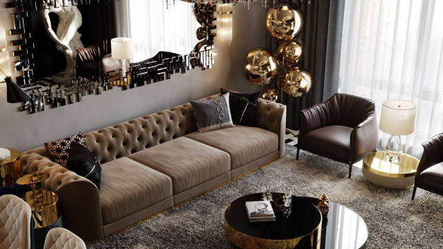 This picture shows a modern living room designed by Antonovich Design. It features a grey sectional sofa, a round metal coffee table, a white TV cabinet with shelving, a large decorative mirror, and two grey arm chairs with ottomans. The walls are painted white and the floor is covered in a light grey rug. There is also a statement light fixture hanging from the ceiling which completes the look of the space.