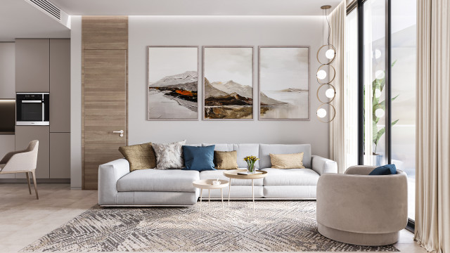 This image is of an interior design project created by Antonovich Designs. It features a white and gold living room with two cream-colored chairs. There is a rug on the floor and a white coffee table between the chairs. On one side of the room, there is a wall of built-in shelving units with glass doors. On the other side, there is a modern fireplace with a white mantel and an interesting abstract art piece on the wall above it.