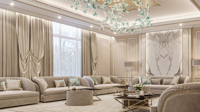 This picture shows an elegant, modern interior design featuring marble-tiled walls, a grand wood staircase, and a luxurious chandelier. The room is illuminated by natural light coming in from the large windows, and furnishings like an armchair, side table and round ottoman complete the stylish look.