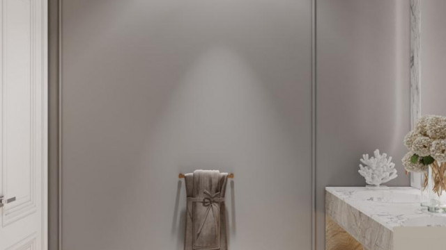 This picture shows a luxurious bathroom interior design. The room features a large marble bathtub with a glass wall in the background, two white pedestal sinks, and a tiled floor. There is also a marble vanity countertop with a seated makeup vanity section, as well as two ornate wall sconces and a decorative mirror.