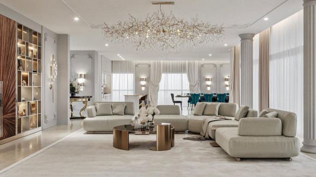 A modern interior featuring a luxurious sitting area of white sofas, cream armchairs and marble tables.