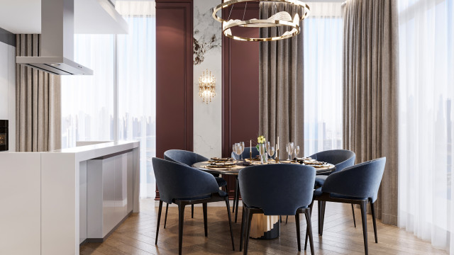 This picture shows a luxurious dining room with a white and gold accent wall behind a large round dining table. There is a beautiful crystal chandelier hanging above the table, and a dark brown wooden floor below. The chairs have white cushions and golden frames, adding to the overall elegance of the room. A few pieces of artwork hang on the accent wall, while a fireplace with a black marble mantelpiece provides a touch of warmth.