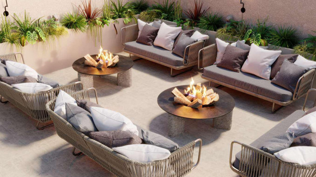 A modern interior featuring a luxurious seating area with a dark leather couch and velvet chairs set against a backdrop of a light blue stone wall.