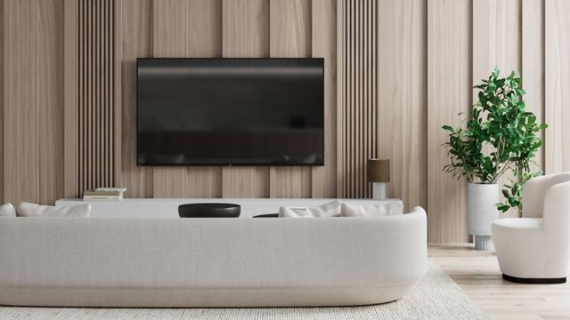 Modern interior design featuring a blue patterned wall, cream couch and matching side chairs, accent table and floor rug, and white shelves filled with decor items.