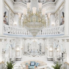 This picture shows a luxurious interior design. The walls are lined with a white marble pattern, and the room features beautiful furniture pieces in a neutral color palette with dark accents. The focal point of the room is a grand coral-colored sofa with gold accents, which sits atop a unique geometric patterned rug. The room is illuminated by multiple chandeliers and spotlights, and it has an overall sophisticated and opulent feel.