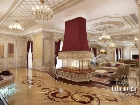 This picture shows an ornately decorated, golden-hued dining room. The walls are lined with intricate floral wallpaper and the furniture is comprised of a large wooden dining table, two matching chairs and a long sofa. A gilded chandelier hangs from the ceiling, while two grand classical paintings adorn the walls. The floor is covered with a soft beige carpet, and the whole atmosphere exudes luxury and sophistication.