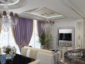 This picture shows a modern, luxury bedroom designed by Antonovich Design. The room features a king-sized bed with a custom-made headboard in light wood and white upholstery. There are two bedside tables with statement lamps on top, as well as a large window looking out onto a balcony. The room has a cream-colored carpet and grey walls, while the ceiling is decorated with a stunning chandelier.