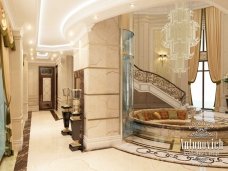 This picture shows a luxurious interior design featuring an elegantly curved white staircase with a grand chandelier suspended from the ceiling. A large framed mirror is hanging above the staircase, providing a grand entrance to the next level of the home. The stairs are lined with a plush red and gold carpet, while stylishly carved wooden railings and balustrades line the walls. On each side of the stairs, two elegant marble statues are placed on pedestals, adding a majestic atmosphere to the home.