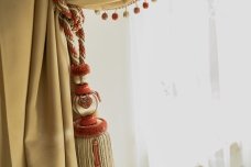 This picture shows a close-up view of a set of chimes made from bamboo tubes, suspended from strings. The tubes are brightly colored and painted with designs of birds and plants, giving them an aesthetically pleasing look. The strings of the chimes hang down from the top of the frame and each tube produces a different sound when struck.