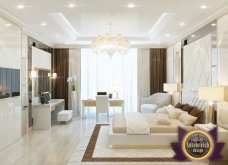 This picture shows a luxurious living room with a contemporary design and style. The room has two cream leather sofas, a wooden coffee table, a stylish chandelier, an ornate sideboard, and various other pieces of stylish furniture. There is also a large window overlooking a pool/pond outside.