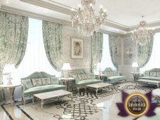 This picture shows a luxurious and grandiose staircase leading into an opulent foyer. The staircase has black marble steps with gilded railings, ornately carved balustrades, and a large crystal chandelier hanging at the base of the stairs. The walls of the foyer are lined with mirrors, giving the space a spacious, regal feel.