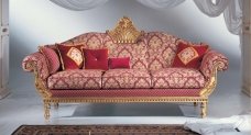 This picture shows a luxurious bedroom with a grand furniture set. The room has a large marble floor and contains a dark, wooden four-poster bed, two comfortable armchairs, a tufted ottoman, a large dresser, and an ornate dresser. The walls are adorned with a unique and fancy wallpaper pattern, while the ceiling is decorated with a beautiful crystal chandelier. The room also has two tall windows with velvet curtains that let in lots of natural light.