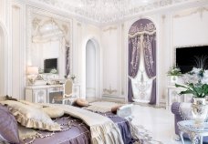 A luxurious living area with distinctive modern design, featuring beautiful marble flooring, plush gold furniture, and an elegant purple chandelier.