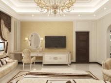 This picture shows a luxurious master bedroom designed with ornate furnishings and decor. The walls feature a stunningly intricate beige and gold wallpaper, while the room is accented with tufted velvet headboards and footboards on each side of the bed. The bed is covered in fur throws, and cushioned armchairs with matching upholstery offer additional seating. A grand chandelier hangs over the bed, and a set of French doors adorned with exquisite draperies open onto a balcony. The room has been expertly styled to create an air of wealth and sophistication.