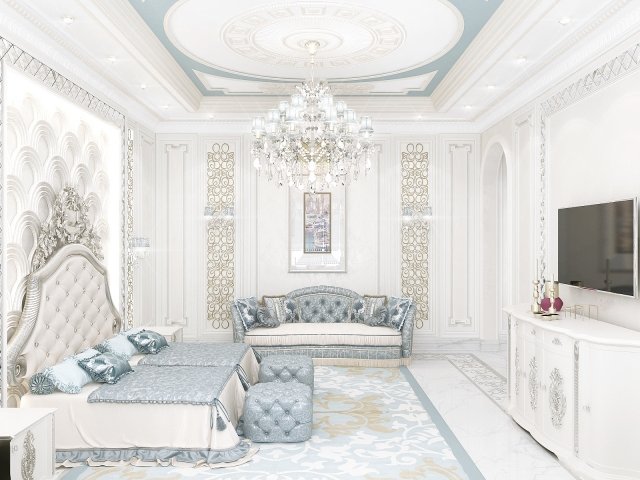 The picture shows a luxurious bedroom. It is decorated in a white and beige color palette with touches of gold accents. The furniture is modern and sleek, and the bed is piled high with pillows and blankets for maximum comfort. A large mirror is hung on the wall, and a crystal chandelier hangs from the ceiling. Other pieces of decor, such as a decorative clock and vases with flowers, add to the elegant atmosphere of the room.