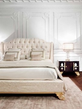 A luxurious master bedroom with a plush bed adorned by velvet pillows and an elegantly wallpapered background.