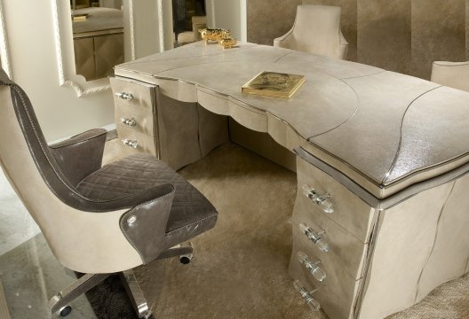 This picture shows a luxurious modern bathroom with a large marble-tiled shower enclosure. The shower is encased in glass walls, and a two-person shower head is mounted on the ceiling. There is a built-in shelf for toiletries and a built-in bench for seating. The walls are lined with intricate marble tiles, and there is a matching marble vanity with dual sinks. Gold-tone accent lighting adds a final touch of luxury to the room.