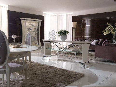 This picture shows a modern room in an elegant residence. The room features a luxurious cream-colored sofa accompanied by two black armchairs and a glass top coffee table. The walls are decorated with bright abstract art pieces, while the floor has a beautiful beige carpet and a glossy oval black tray table. There is also a large green potted plant in the corner which adds a touch of nature to the luxurious atmosphere.