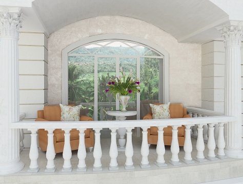 This picture shows an outdoor seating area within a modern contemporary garden setting. The area features a white sofa and cushions, surrounded by plants and trees. There is a small round coffee table with a white ceramic top in the centre, with a pot of green plants next to it. A light yellow rug is spread across the floor, and a three-tiered fountain is situated in the background, with a birdbath at the top.