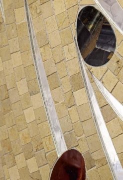 The picture appears to be a white spiral staircase in a home. It is made of white metal with wooden treads, and there is a railing along both sides. The stairway is illuminated by natural light coming in through a window.