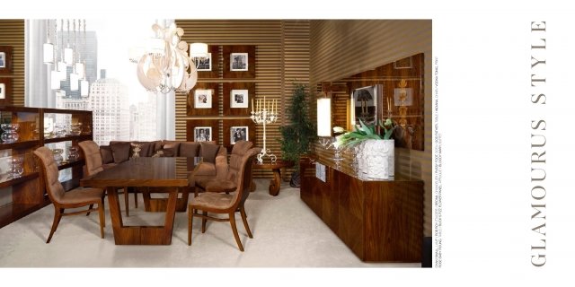 This picture shows a luxurious dining room in a modern home. The room features a large circular table with several chairs, a stylish lighting fixture hanging over the table, and a large chandelier in the center of the room. The walls are covered in a light grey and the floor appears to be made of dark brown or black marble. Decorative items such as artwork and vases can be seen throughout the room.