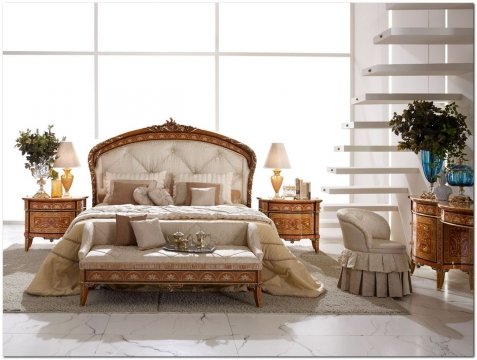 This picture shows a luxurious modern living room with a large white sectional sofa, glass coffee table and matching armchairs. The walls and ceiling are paneled in wood and decorated with intricate golden accents. The warm orange and brown hues of the floor tiles complement the natural wood furnishings, while the tall windows flood the room with light. A crystal chandelier hangs in the center of the room, adding a touch of elegance to the space.