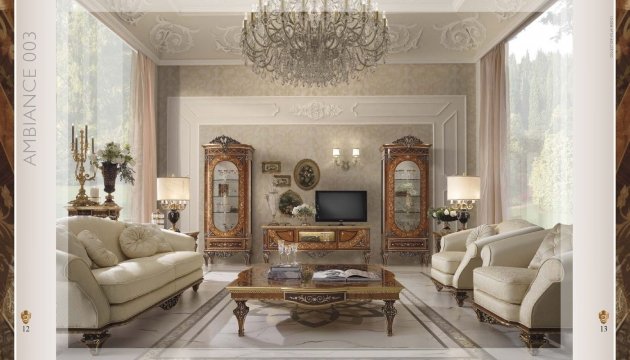 This picture shows a luxurious bedroom with a white tufted headboard and matching bed frame. There is also a white upholstered ottoman at the foot of the bed and two matching nightstands on either side. The walls and ceiling are finished in a light gray color, while the floors are covered in a plush off-white carpet. On the walls, there are several pieces of artwork and the room is finished with some decorative accessories.