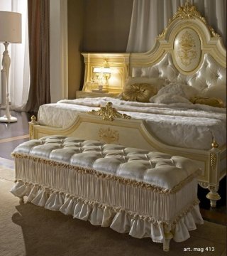 A modern luxury living room with white walls, crystal chandelier, and large beige sofas surrounded by chic golden decorations.