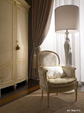 This picture shows a luxurious living room with high-end furniture and decor. The room features a white sofa set with two arm chairs placed on a patterned rug in front of a large stone fireplace. There is an ornate gold-framed mirror and a crystal chandelier hanging from the ceiling. The walls are painted a deep shade of blue and have ornate carved wood accents along with framed paintings. The space is also filled with lush green plants and flowers for decoration.