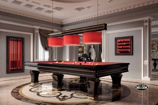 This picture shows a luxurious modern bedroom with floor-to-ceiling windows and a balcony. The walls are white, with black and silver accents. The bed is a tall four-poster bed with white sheets and a black and silver headboard. A large crystal chandelier hangs over the bed, adding sparkle to the room. To the side of the bed is a small table, with a white armchair beside it. To the right of the bed is a window seat, and beyond are the wide windows and balcony doors.